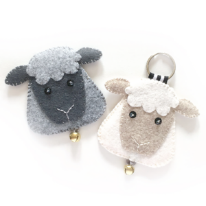 Two felt sheep ornaments, one gray and one white, each with a keychain attachment and a small golden bell.