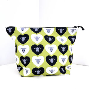 A large zippered pouch with a pattern of black and white sheep faces inside heart shapes on a bright green background.