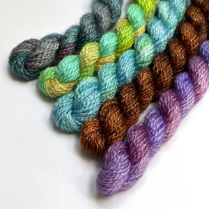 An array of soft, multicolored yarns displayed in a sequence, highlighting their plush textures and diverse colors.