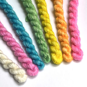 Colorful yarns arranged in a spectrum from blue to green to yellow, showcasing a variety of textures.