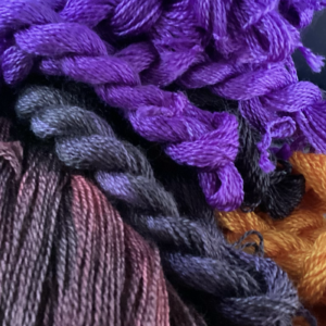 An assortment of purple and dark-colored yarns and threads bundled together, showcasing various shades and textures.