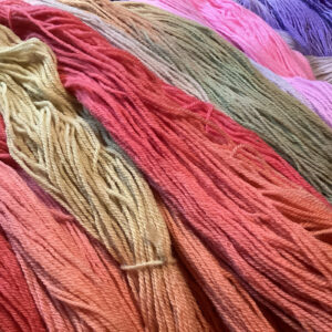 Soft yarns in a gradient of sunset colors, including pink, orange, and yellow, arranged to showcase their plush texture.