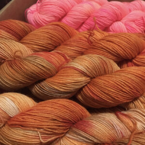 Bundles of yarn in soft pastel colors including pink, orange, and beige, displayed in a cozy setting.